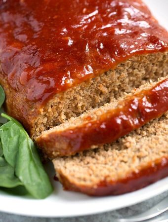 Tasty Turkey Meatloaf on white plate next to baby spinach
