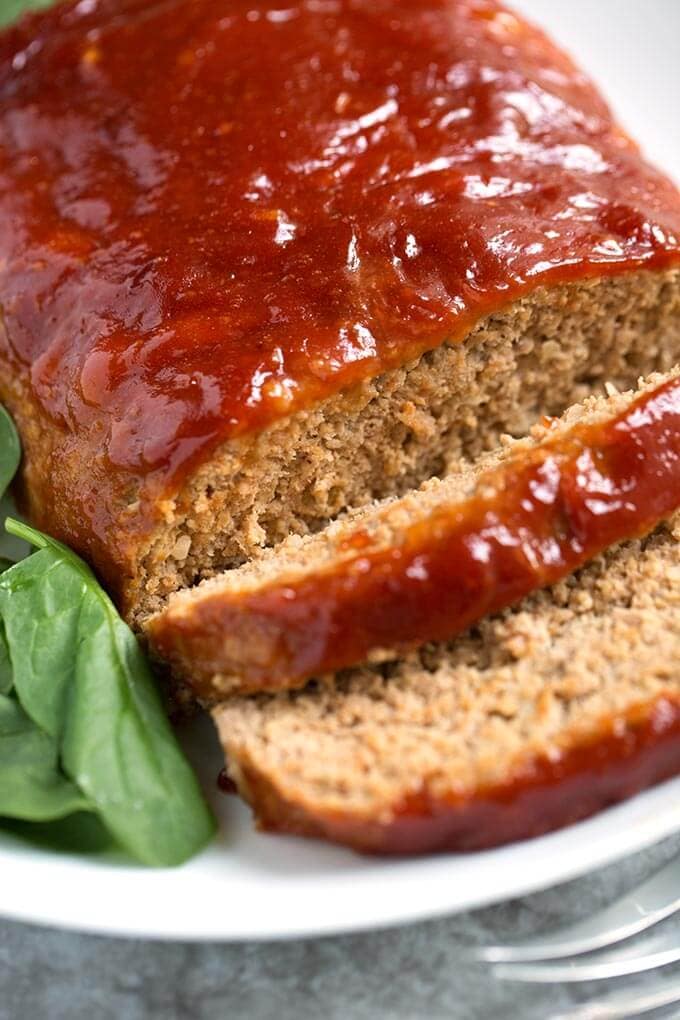 Tasty Turkey Meatloaf on white plate next to baby spinach