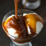 Caramel sauce poured on to vanilla ice cream in small glass serving bowl