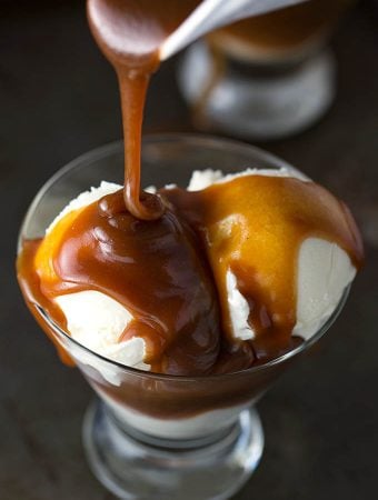 Caramel sauce poured on to vanilla ice cream in small glass serving bowl