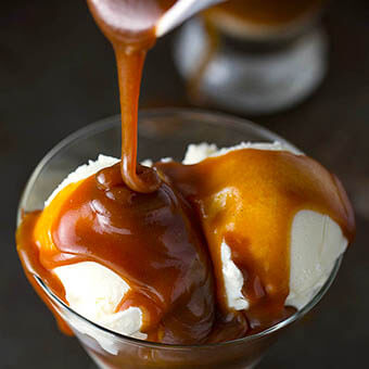 Caramel Sauce poured on vanilla ice cream in small glass bowl