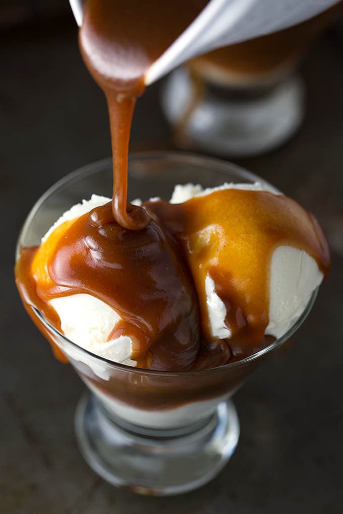 Caramel sauce poured on to vanilla ice cream in small glass serving bowl
