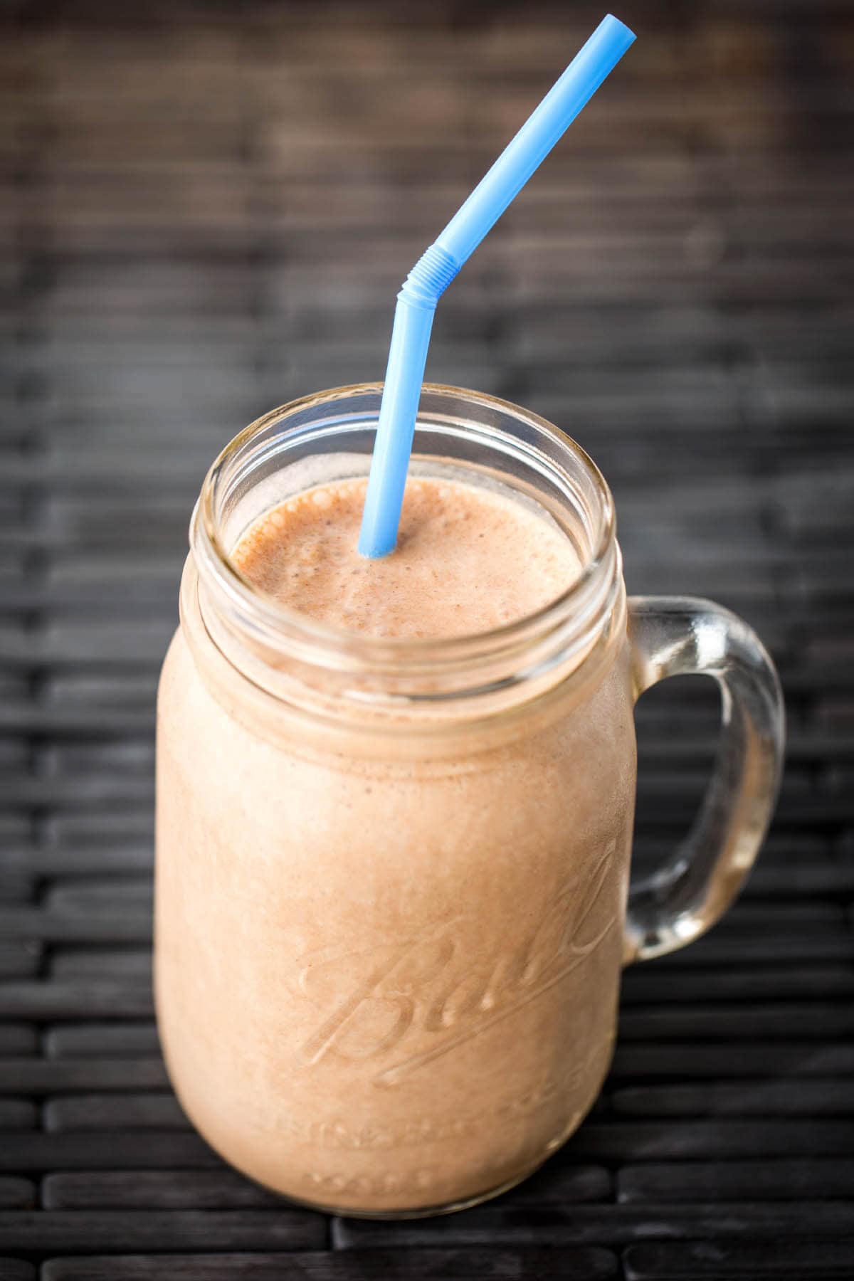 Chocolate Peanut Butter Banana Smoothie in glass Ball jar with blue straw