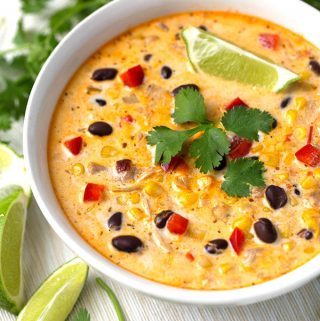 Crock Pot Mexican Corn Chicken Soup in white bowl garnished with cilantro leaves and lime wedges