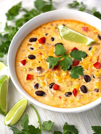 Crock Pot Mexican Corn Chicken Soup in white bowl garnished with cilantro leaves and lime wedges