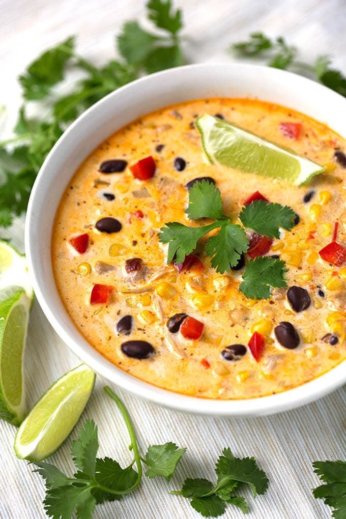 Crock Pot Mexican Corn Chicken Soup in white bowl garnished with cilantro leaves and lime wedges