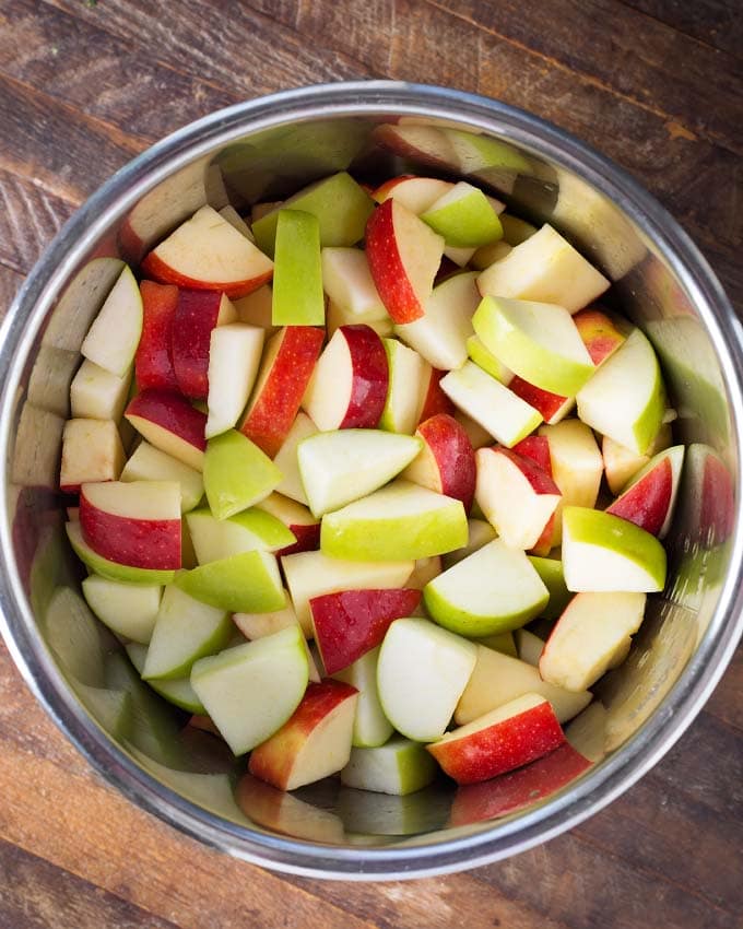 chopped red and green apples in pot on wooden board