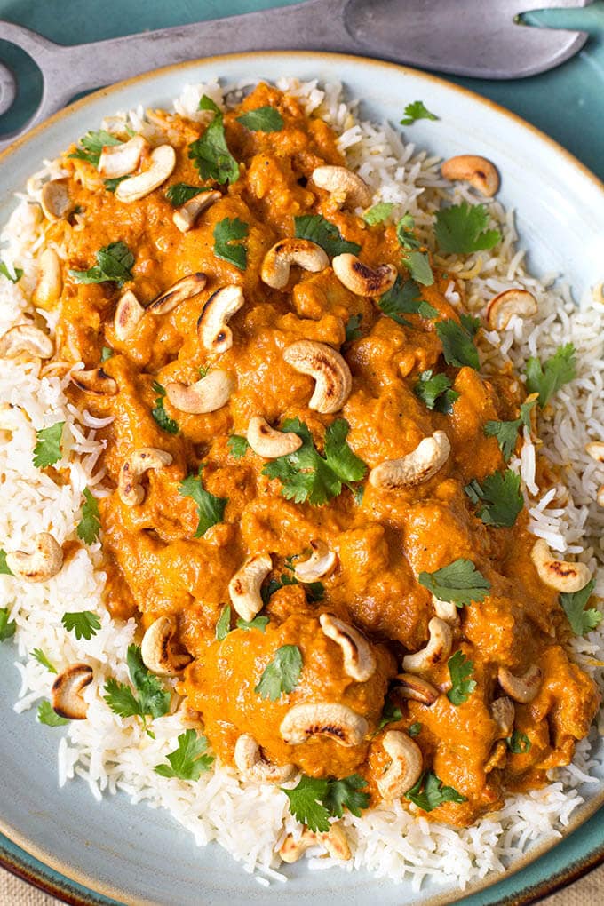  Butter Chicken topping rice topped with cashews on white plate