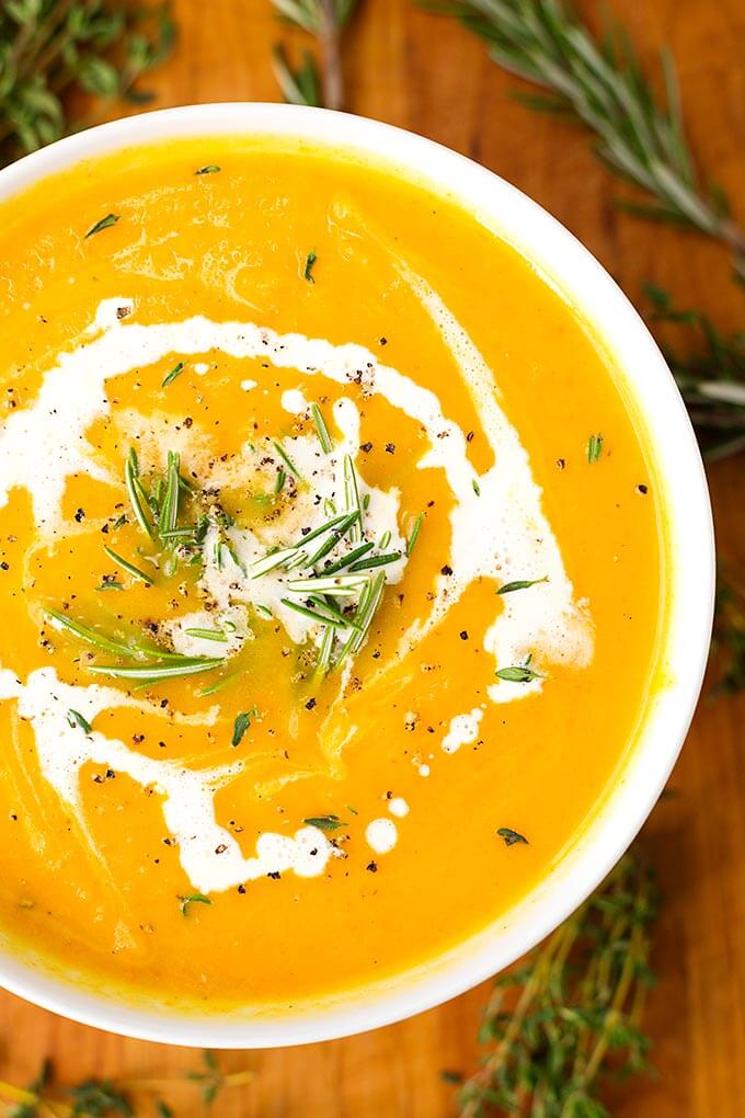 Instant Pot Butternut Squash Soup in a white bowl surrounded by rosemary