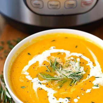  Butternut Squash Soup in a white bowl garnished with rosemary with pressure cooker in background