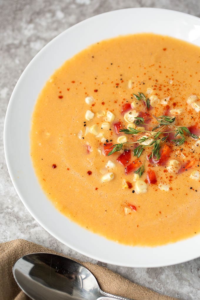 Close up of Fresh Corn Soup in a shallow white bowl next to silver spoon