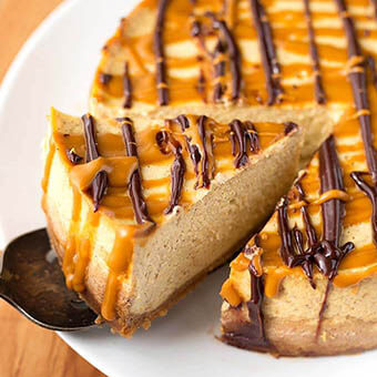 Slice of Pumpkin Cheesecake on white plate being lifted from the cake by a serving spoon