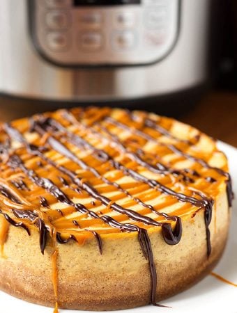 Whole Pumpkin Cheesecake on white plate with pressure cooker in background