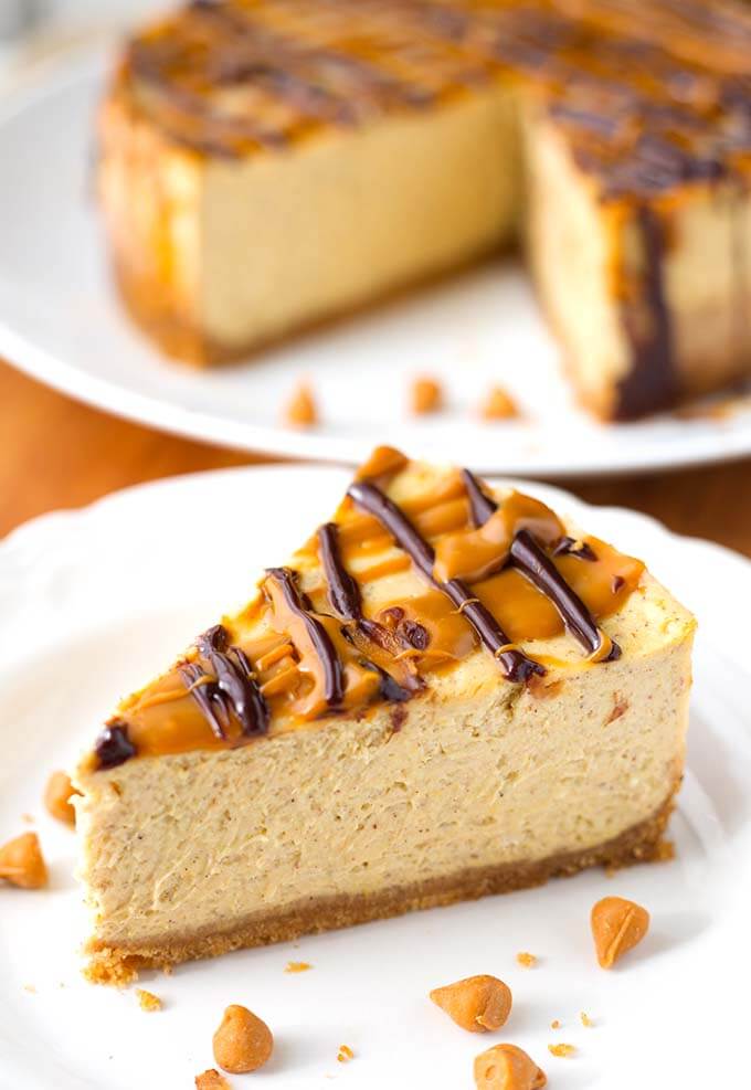 Slice of Pumpkin Cheesecake on white plate with cheesecake in background