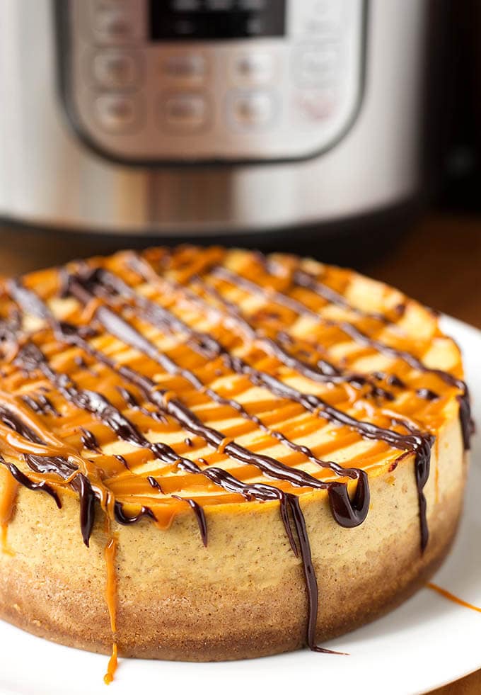 Whole Pumpkin Cheesecake on white plate with pressure cooker in background