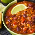 Chili in a two tone green bowl garnished with lime wedge
