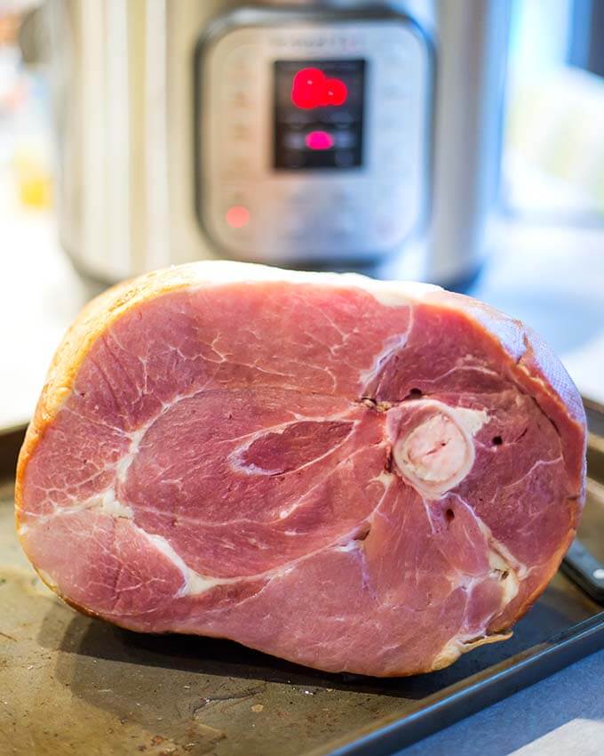 Bone-in Ham on baking sheet with pressure cooker in background