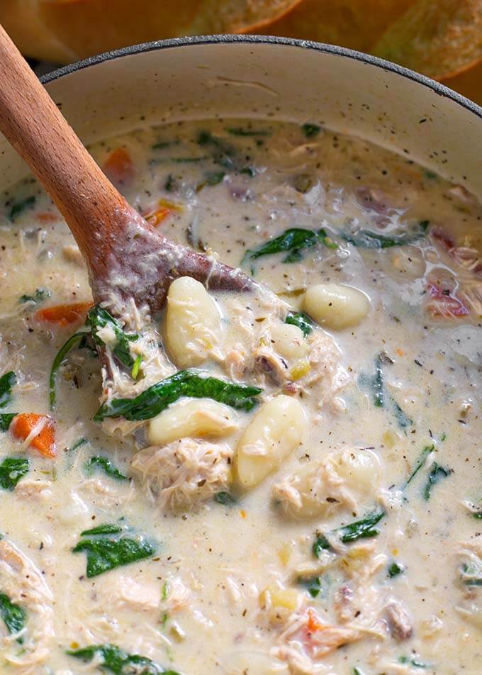 Wooden spoon stirring Creamy Chicken Gnocchi Soup in a bowl