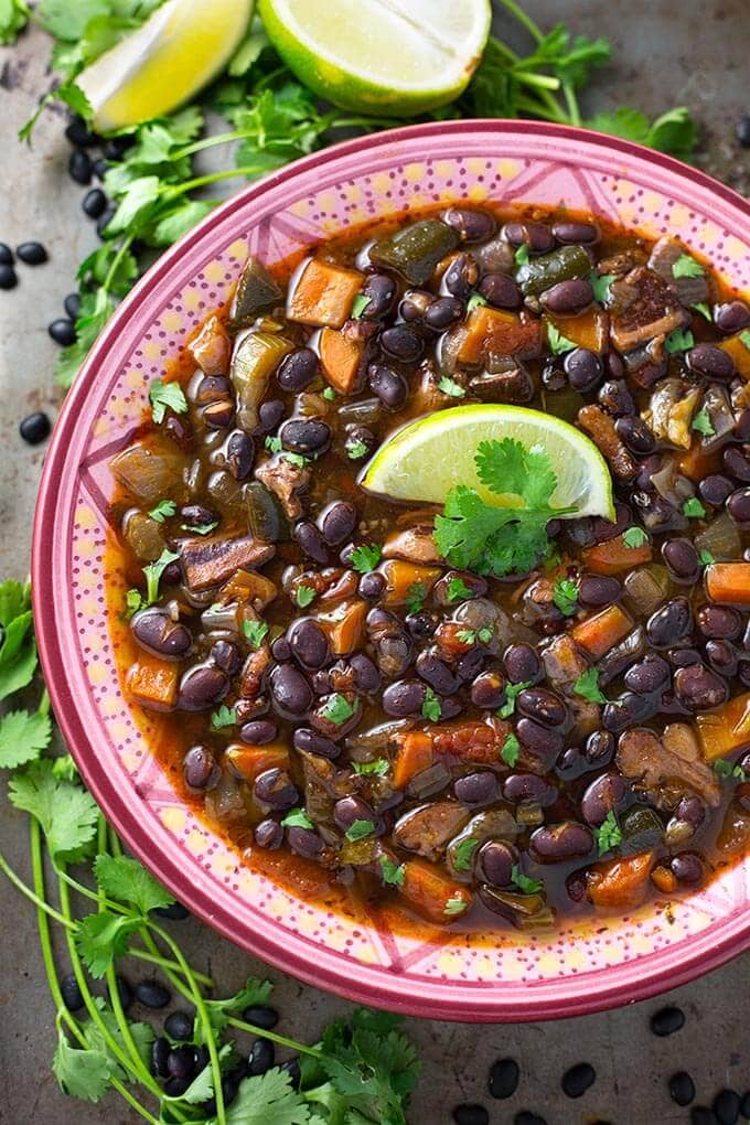 Black Bean Soup in a pink patterned bowl topped with a slice of lime and fresh cilantro