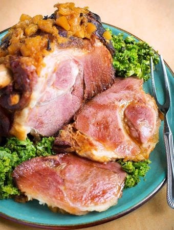 Bone-in Ham on turquoise plate with fork and green leaf garnish