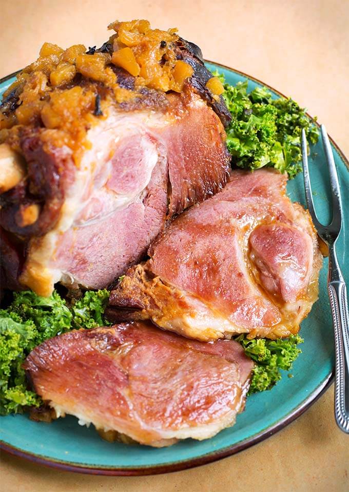 Bone-in Ham on turquoise plate with fork and green leaf garnish