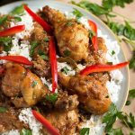 Chicken Adobo Filipino with rice on a white plate garnished with red peppers and cilantro