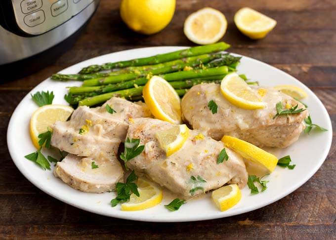 Creamy Lemon Chicken with asparagus on a white oblong plate on wooden table