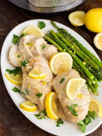 Creamy Lemon Chicken with asparagus on a white oblong plate on wooden table