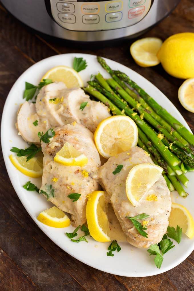 Creamy Lemon Chicken with asparagus on a white oblong plate on wooden table