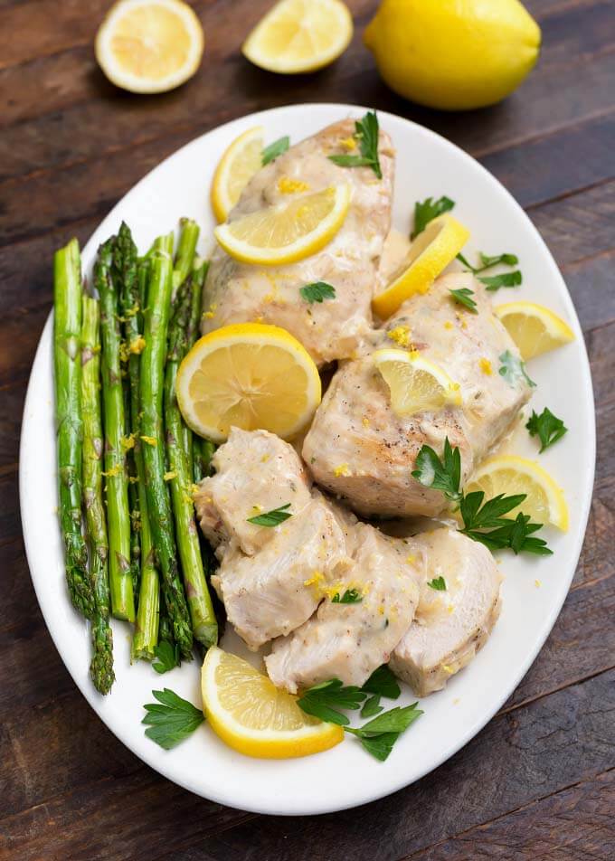 Creamy Lemon Chicken with asparagus on a white oblong plate on wooden table
