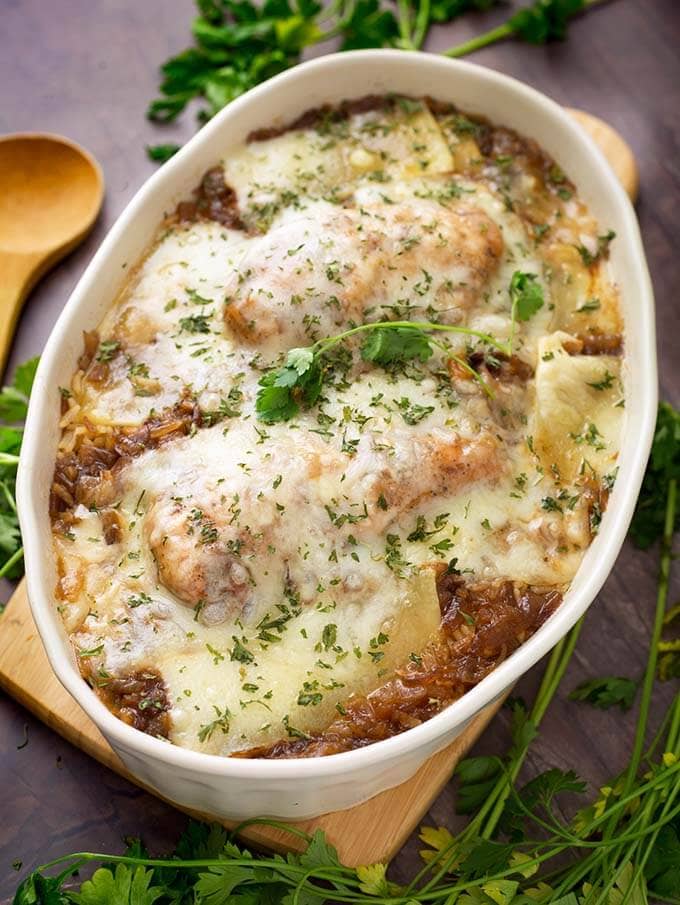 French Onion Chicken and Rice in a white oval shaped bowl on a small wooden board