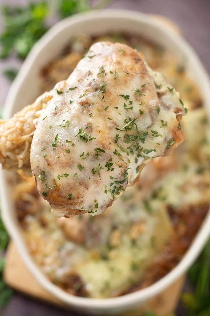 Close up of spoonful of French Onion Chicken and Rice with casserole dish in background