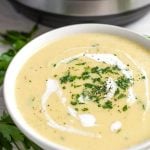 Potato Leek Soup in a white bowl with a pressure cooker in the background