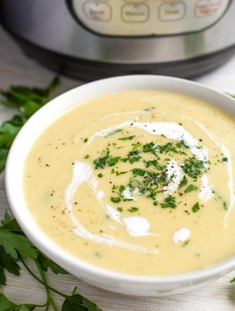 Potato Leek Soup in a white bowl with a pressure cooker in the background