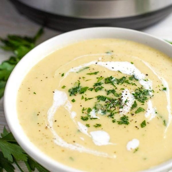 Potato Leek Soup in a white bowl with a pressure cooker in the background