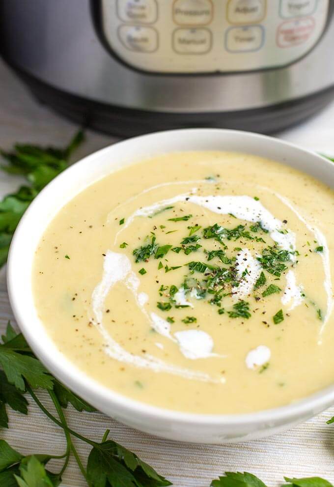Potato Leek Soup in a white bowl with a pressure cooker in the background