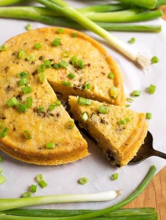 Cut Slice of Southwest Corn Pudding garnished with green onion being lifted from rest of pudding