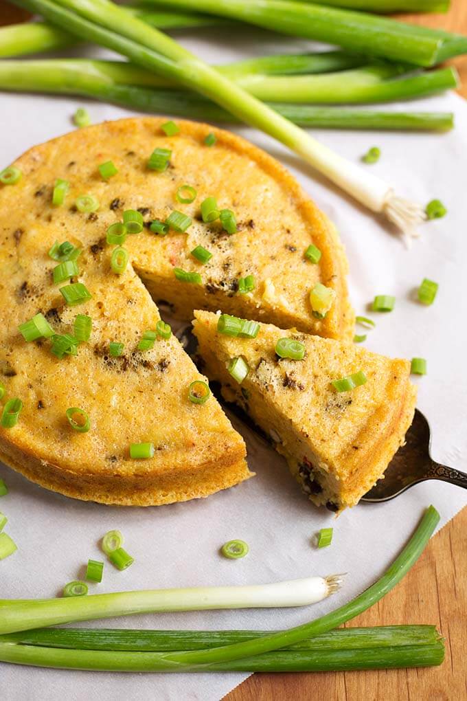 Cut Slice of Southwest Corn Pudding garnished with green onion being lifted from rest of pudding