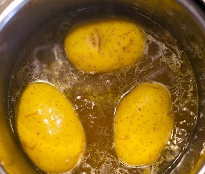 three gold potatoes cooking in the turkey drippings