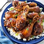 Sticky Chicken Drumsticks with rice on a blue plate next to silver fork