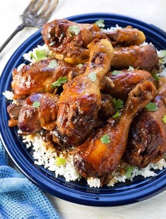 Sticky Chicken Drumsticks with rice on a blue plate next to silver fork