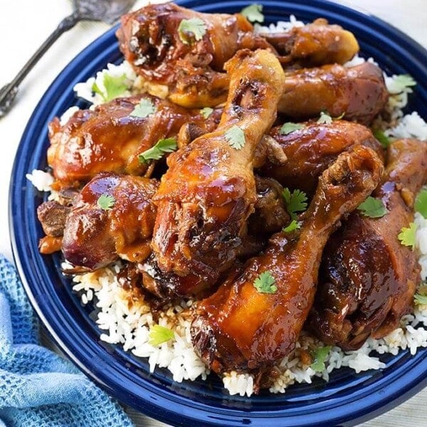 Sticky Chicken Drumsticks with rice on a blue plate next to silver fork