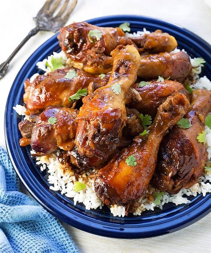 Sticky Chicken Drumsticks with rice on a blue plate by silver fork