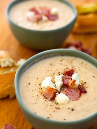 Two grey bowls of Cauliflower Bacon Chowder on a wooden board