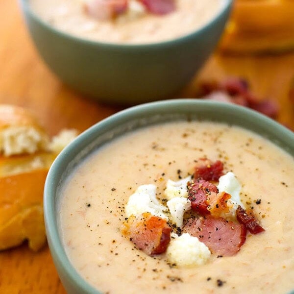 Two grey bowls of Cauliflower Bacon Chowder on a wooden board