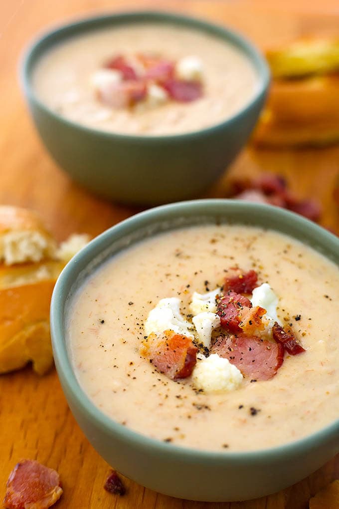 Two grey bowls of Cauliflower Bacon Chowder on a wooden board