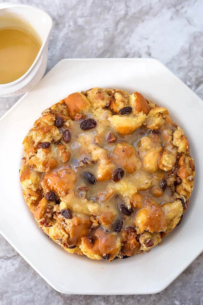 Bread Pudding on a white plate next to custard in cup