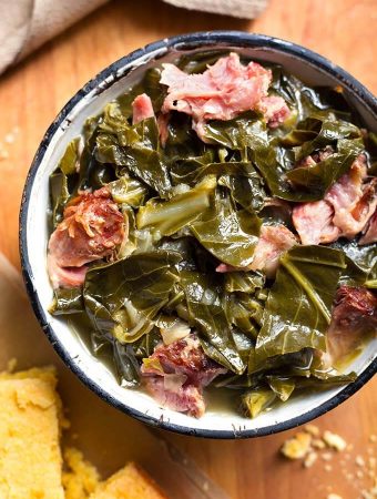 Instant Pot Collard Greens with a ham hock in a bowl with black rim on wooden board