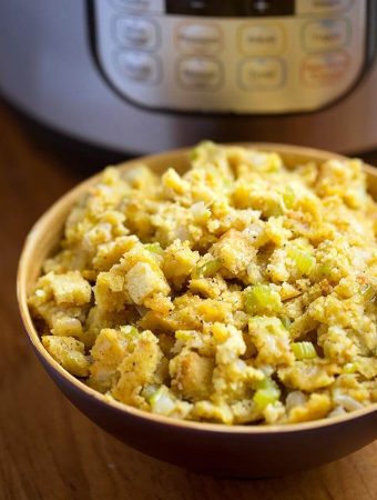 Instant Pot Cornbread Stuffing in a beige bowl with pressure cooker in background