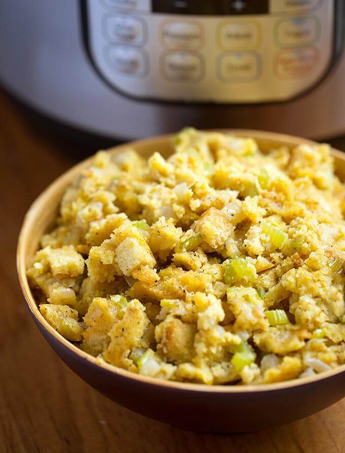 Cornbread Stuffing in a brown bowl in front of a pressure cooker